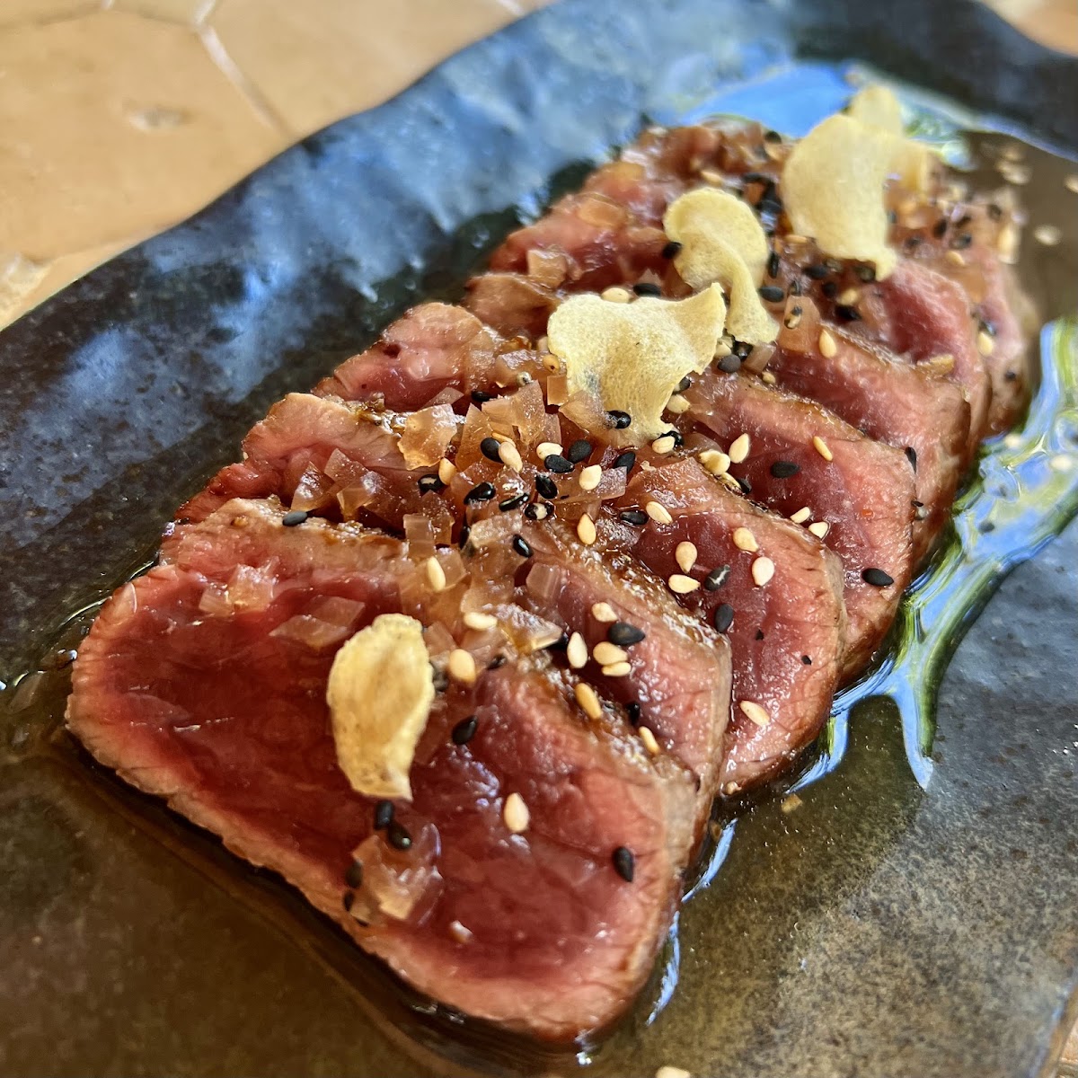 Finas láminas de carne japonesa con ajo frito y semillas